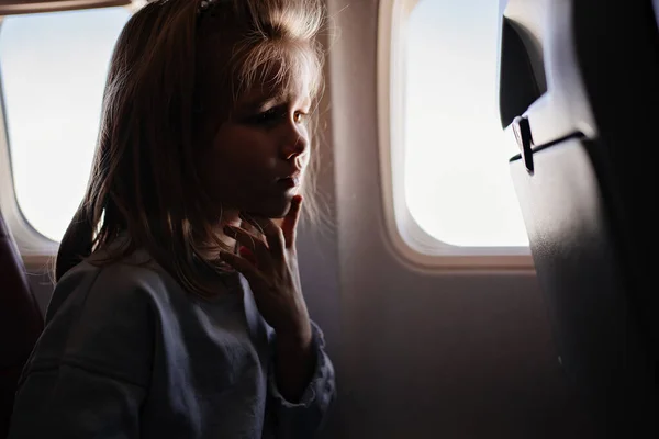 Una niña pequeña y sujeta por la garganta debido a la enfermedad en un avión — Foto de Stock