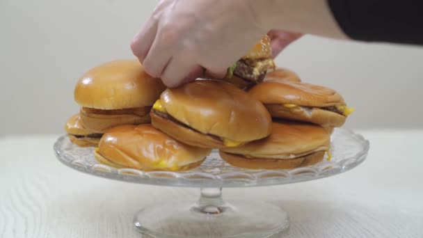 Mains placent cheeseburgers sur un plat en verre rond. restauration rapide. gâteau original. — Video