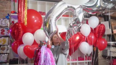 Bir kadın doğum günü için büyük gümüş bir rakam şeklinde bir balon şişirir.