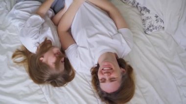 Üstü görünüyor. Anne ve kızı yatakta gıdıklanarak gülüyorlar. çocuk oyunları