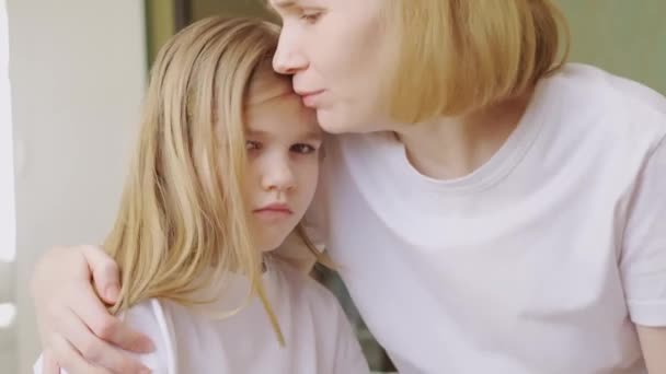 Мама обіймає і втішає свою засмучену маленьку доньку вдома . — стокове відео