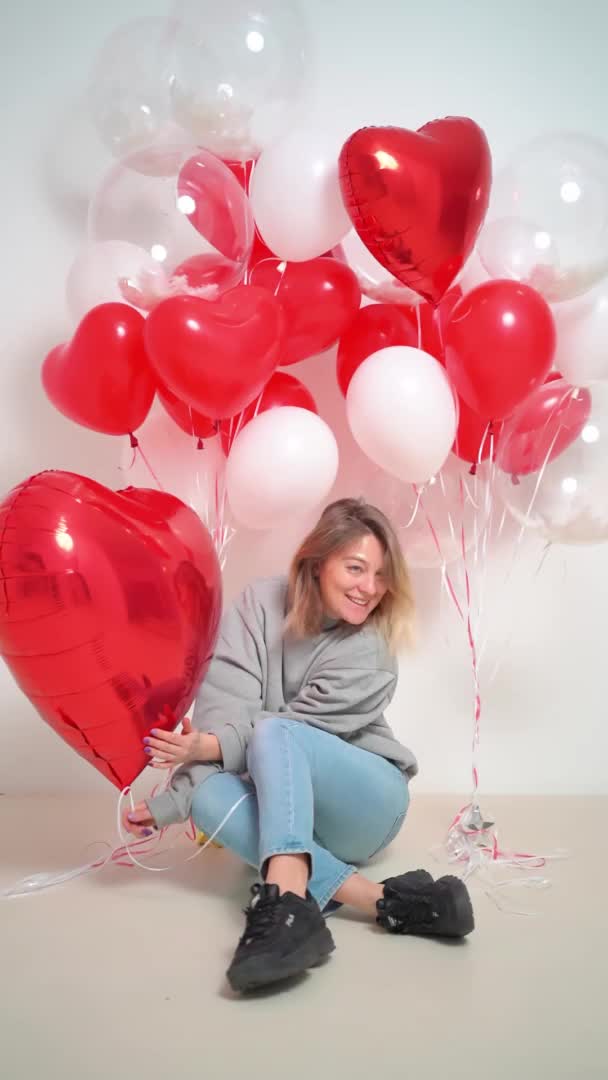 Una mujer rubia divertida con globos sobre un fondo blanco. — Vídeo de stock