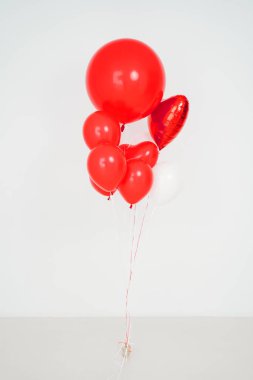 Beyaz zemin üzerinde top ve kalp şeklinde kırmızı ve beyaz balonlar.