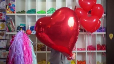 Kadın dans eder ve kalp şeklinde büyük kırmızı bir folyo topuyla.