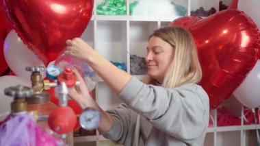 Kadın helyumla şişiyor içinde beyaz tüyler olan saydam bir balon.. 
