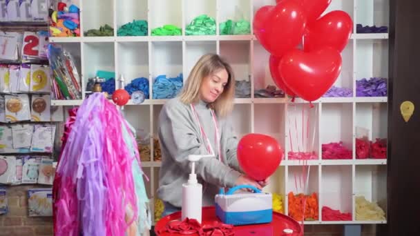 Trabalho aerodesigner. mulher estende balão antes de inflar com bola vermelha de hélio — Vídeo de Stock