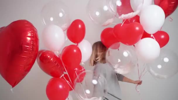 Een blonde vrouw danst en heeft plezier met ballonnen Valentijnsdag — Stockvideo