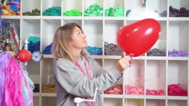 Bir kadın kalp şeklinde şişirilmiş helyum kırmızı balonuna kurdele bağlar. 