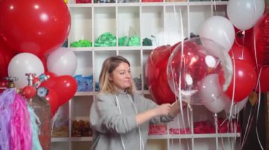 Kadın kurdeleyle bağlanıyor. Yuvarlak saydam bir balon. İçinde beyaz tüyler var..