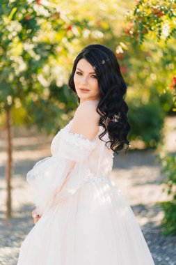 Güzel esmer gelin, parkta Rowan ağaçlarıyla gelinlik giymiş.. 