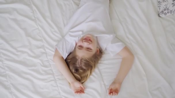 Överst. En liten flicka skrattar med kittling på sängen. spel av barn — Stockvideo