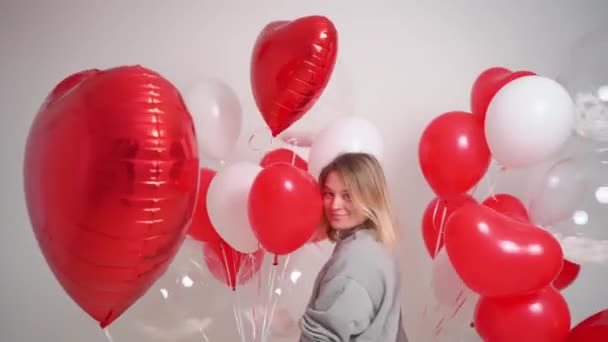 Uma mulher loira dança e se diverte com balões em um fundo branco. — Vídeo de Stock