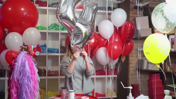 Μια γυναίκα φουσκώνει ένα μπαλόνι σε σχήμα ενός μεγάλου ασημένιου αριθμού για τα γενέθλιά της. — Αρχείο Βίντεο
