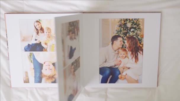 Χέρια μετακινηθείτε μέσα από σελίδες του photobook σε λευκό φόντο. οικογενειακή φωτογράφιση — Αρχείο Βίντεο