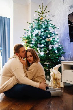 Mutlu ve sevgi dolu bir çift Noel ağacının orada oynaşıyor ve sarılıyorlar.