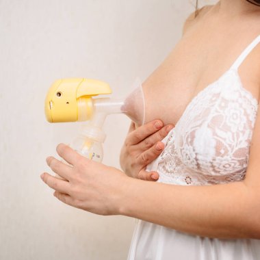 Bir kadın beyaz arka planda meme pompası kullanıyor. Yazı için boşluk. 