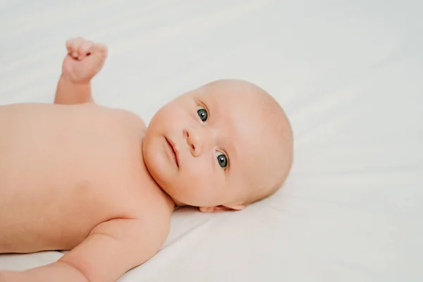 Lindo bebé sin ropa en una sábana blanca. pediatría. piel sana —  Fotos de Stock