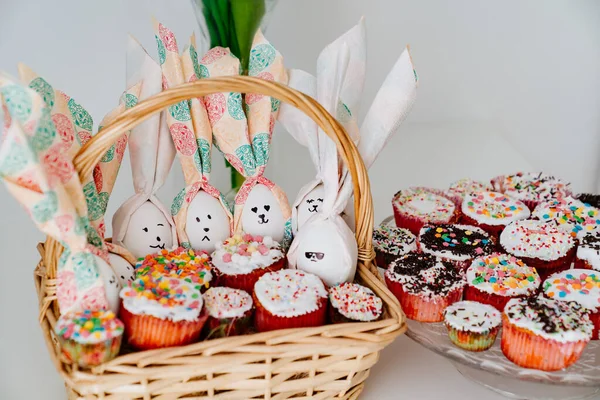Cesta com ovos decorados e bolos de Páscoa ou muffins. — Fotografia de Stock