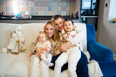 Büyük, mutlu bir aile mutfaktaki evin kanepesinde oturur..