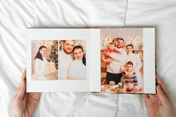Руки с книгой с фотографиями большой семьи на белом фоне. — стоковое фото