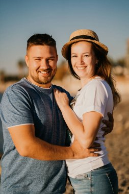 Bir adam ve bir kadın kumsalda birbirlerine sarılıyorlar. Tatil köyünde yeni evliler. parlak güneş.