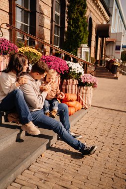 Sonbahar çiçekleriyle süslenmiş merdivenlerde küçük bir çocukla mutlu bir aile.. 