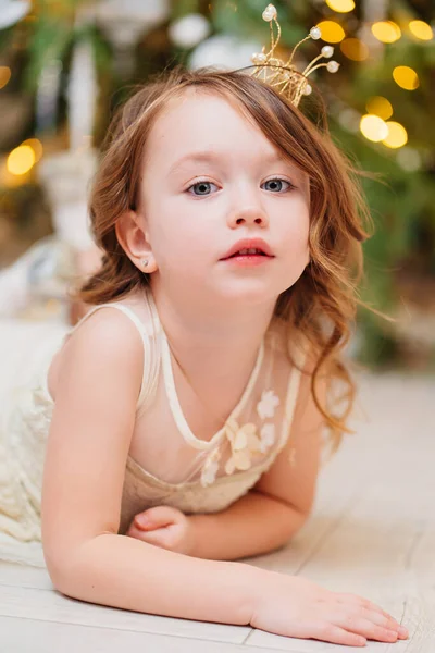 Uma menina bonito faz um desejo e espera por Papai Noel sob a árvore de Natal. — Fotografia de Stock