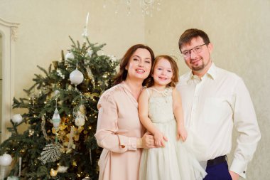 Noel ağacının yanında mutlu bir aile. Yeni yılı evde kutlama geleneği