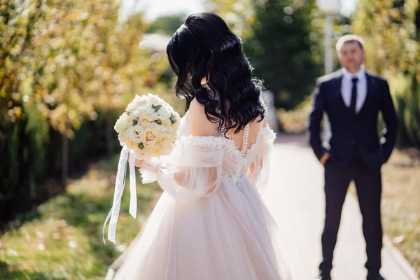 Concentration sélective. le marié regarde la mariée sur un chemin dans le parc. — Photo