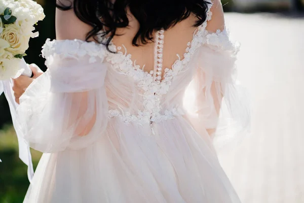 Der Rücken eines weißen Brautkleides auf der Braut. — Stockfoto