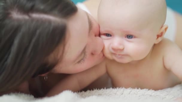 母親はベッドの上で赤ん坊を抱きかかえて拭き取る。接近中だ。母親の愛とケア. — ストック動画