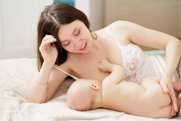 A mother feeds the baby with breast milk on the bed. the breastfeeding. — Stock Photo, Image