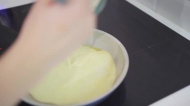 Bir kadın omlet hazırlar ve bir tavaya süt ve yumurta karışımı döker.