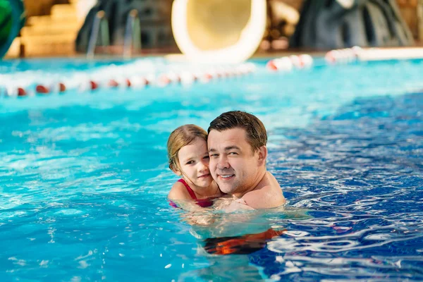 Papá y su hija se abrazan y nadan en la piscina. entrenamiento de natación. — Foto de Stock