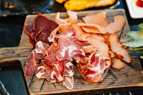 М'ясо розрізається на дерев'яній обробній дошці. сушене м'ясо делікатесу . — стокове фото