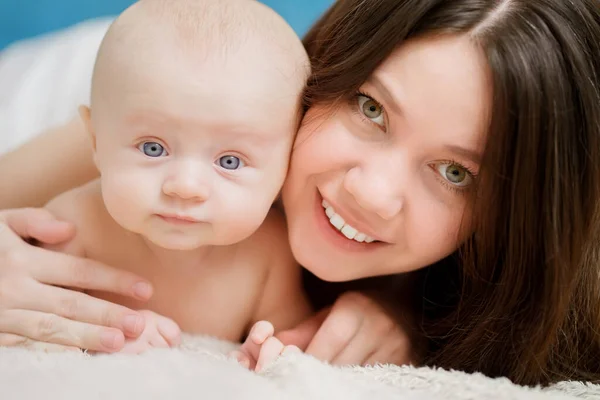 Mamá abraza al bebé en la cama. Primer plano. amor y cuidado materno. —  Fotos de Stock