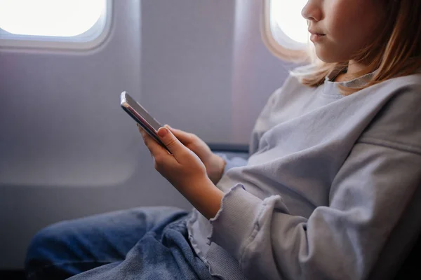 한 어린 소녀가 비행기 좌석에서 스마트폰으로 게임을 하고 있습니다 — 스톡 사진
