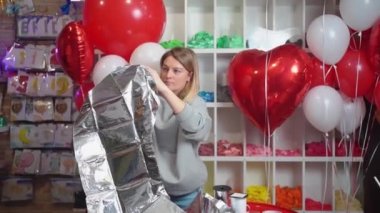 Bir kadın doğum günü için büyük gümüş bir rakam şeklinde bir balon şişirir.