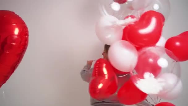 Een blonde vrouw danst en heeft plezier met ballonnen op een witte achtergrond. — Stockvideo