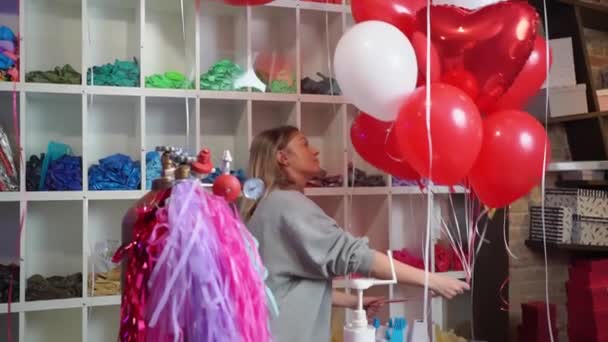 Kadın, beyaz, kırmızı, folyo balonlardan kalp ve top şeklinde kompozisyon yapar.. — Stok video