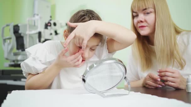 Офтальмолог учит девочку надевать ортокератологические контактные линзы — стоковое видео