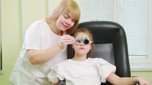 Ögonläkare diagnostiserar små flickor vision och gör urval av linser. — Stockvideo