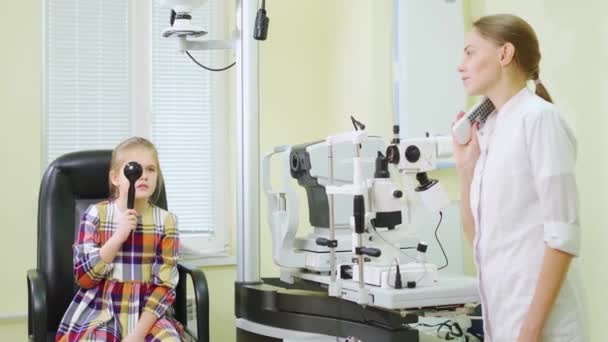 Seorang dokter mata mendiagnosa penglihatan seorang gadis kecil pada proyektor tanda. — Stok Video