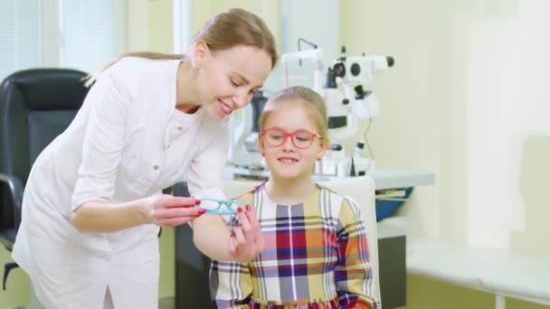 Göz doktoru klinikteki randevusunda küçük bir kız için gözlük alıyor. — Stok video