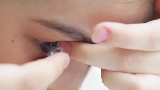 Close-up uma menina para colocar em lentes de contato com os dedos e pisca. — Vídeo de Stock