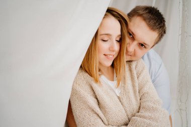 Mutlu ve sevgi dolu bir çift beyaz bir perdenin arkasında sarılıyor.. 