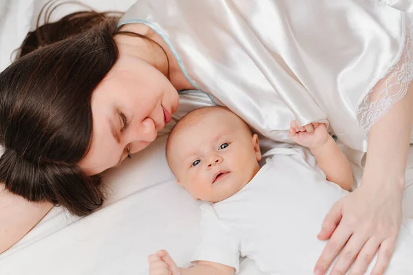 Mamá se acuesta con el bebé en la cama. la felicidad de la maternidad. — Foto de Stock