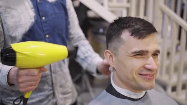 Cabeleireiro seca secador de cabelo morena homem em uma barbearia — Vídeo de Stock
