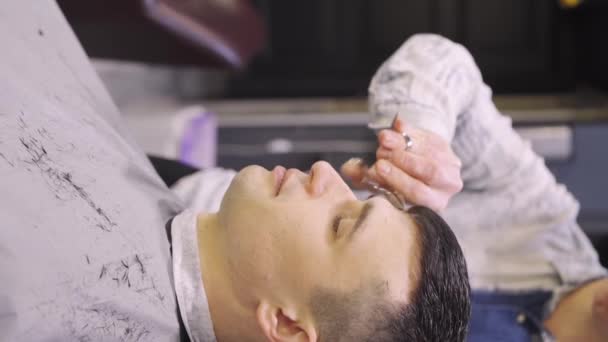Вертикальное видео. парикмахер делает стрижку для мужчин с ножницами в парикмахерской — стоковое видео