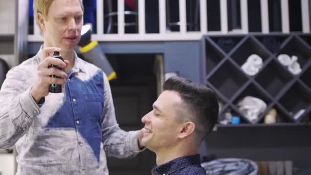 O cabeleireiro styling um homem morena e pulverização hairspray em uma barbearia — Vídeo de Stock